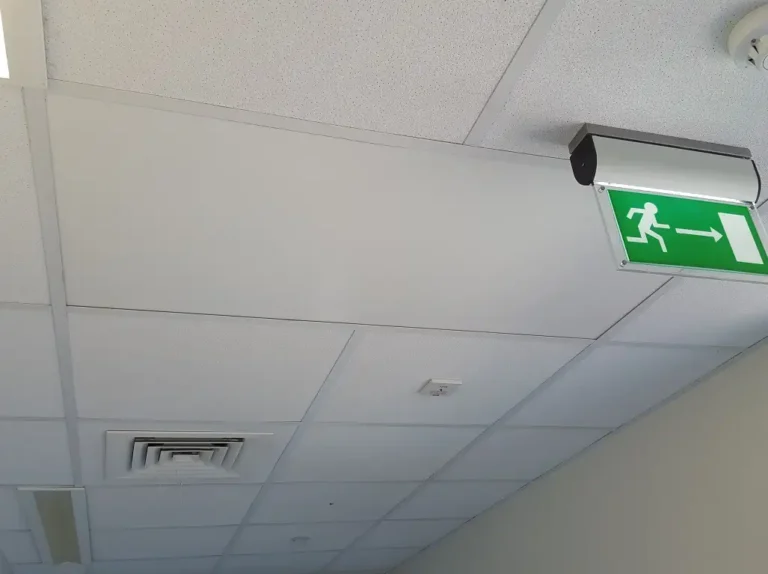 A ceiling with an emergency exit sign and a ventilation grille visible.